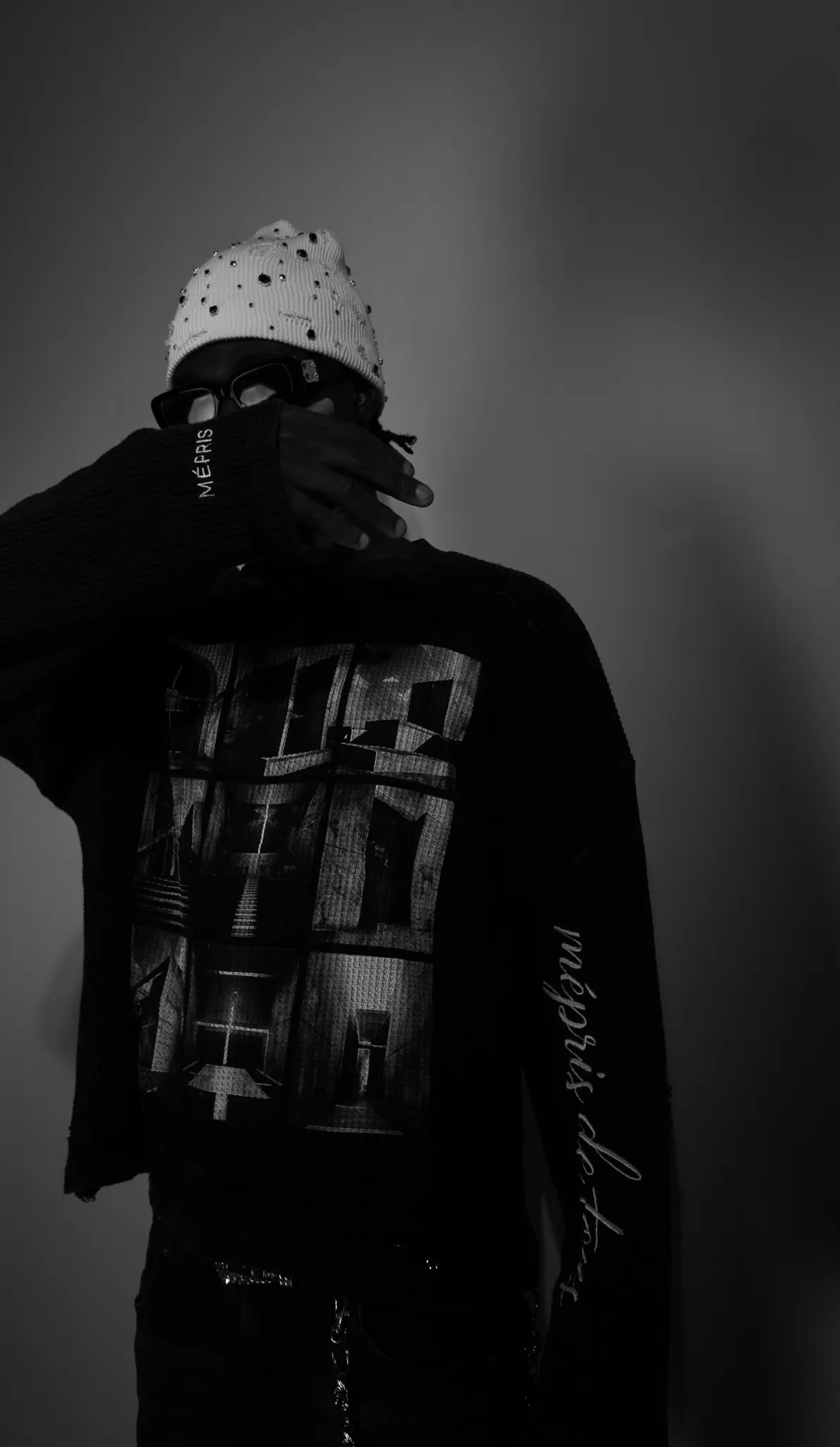 Minimalist black and white fashion portrait of a model wearing a studded beanie and glasses