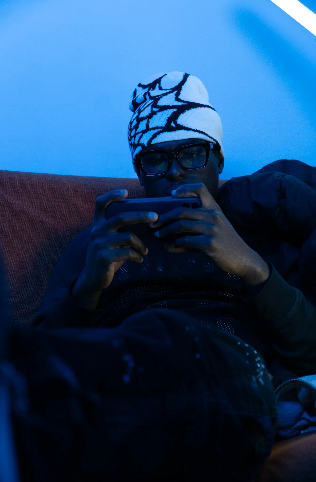 Brand lifestyle photography of a model looking at a smartphone under cool blue lighting